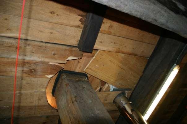 Figuur 35 Onderzijde kapzolder. De beide luiken in de zolder, ter weerszijden van de spil, zijn zwaar beschadigd. Bij de toegekeerde hoek van de spil zit een schil.
