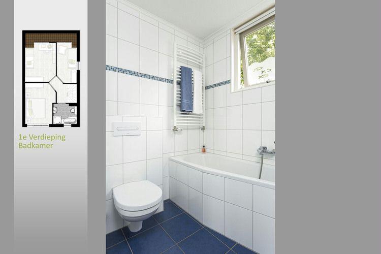 De badkamer is wit betegeld tot aan het plafond, met een blauwe mozaïekstrip en blauwe vloertegels als kleuraccent.
