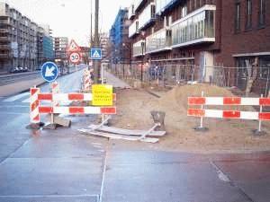 De tegels voel je met je voeten en de groene struiken/gras vormen een lijn die een blinde goed kan volgen.