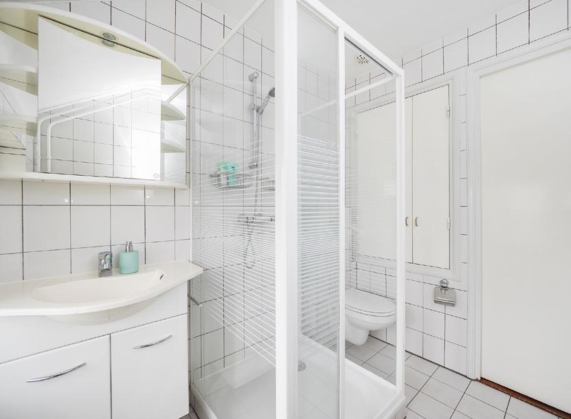2 de geheel betegelde badkamer met een douchecabine, inbouwcloset en vaste wastafel in