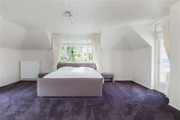 . De riante masterbedroom is speels ingedeeld en voorzien van vloerbedekking, stucwerk