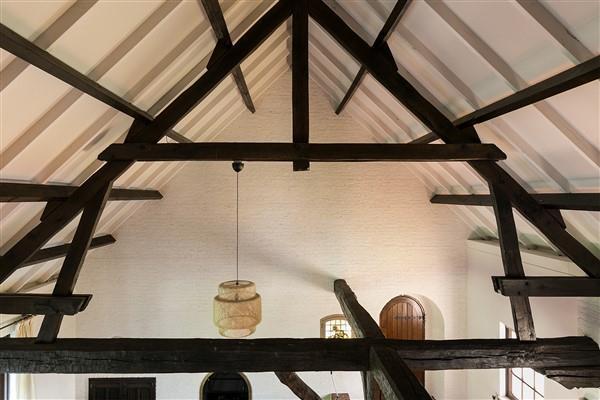 De vide, met zicht op de woonkamer, is afgewerkt met vloerbedekking, schoonmetselwerk wanden en een houten balken plafond.
