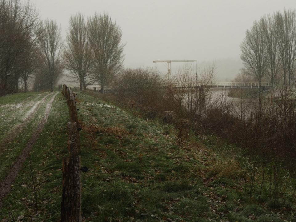 Blijf ongeveer een kilometer langs de Regge lopen tot aan de houten ophaalbrug. Steek de Regge over en loop door tot aan een kruising van paden bij een groot huis met rieten dak.