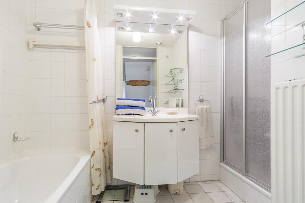 Badkamer Een geheel betegelde badkamer welke is voorzien van een ligbad met handdouche,