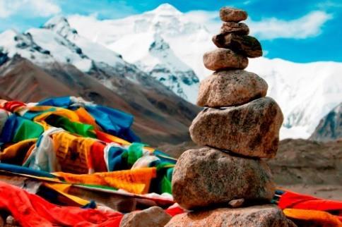 Tibetaans grondgebied. Zover je kunt kijken zie je de witte toppen van het Himalaya-gebergte. Gebedsvlaggen wapperen in de wind en stapeltjes mani-stenen sieren het woeste landschap.