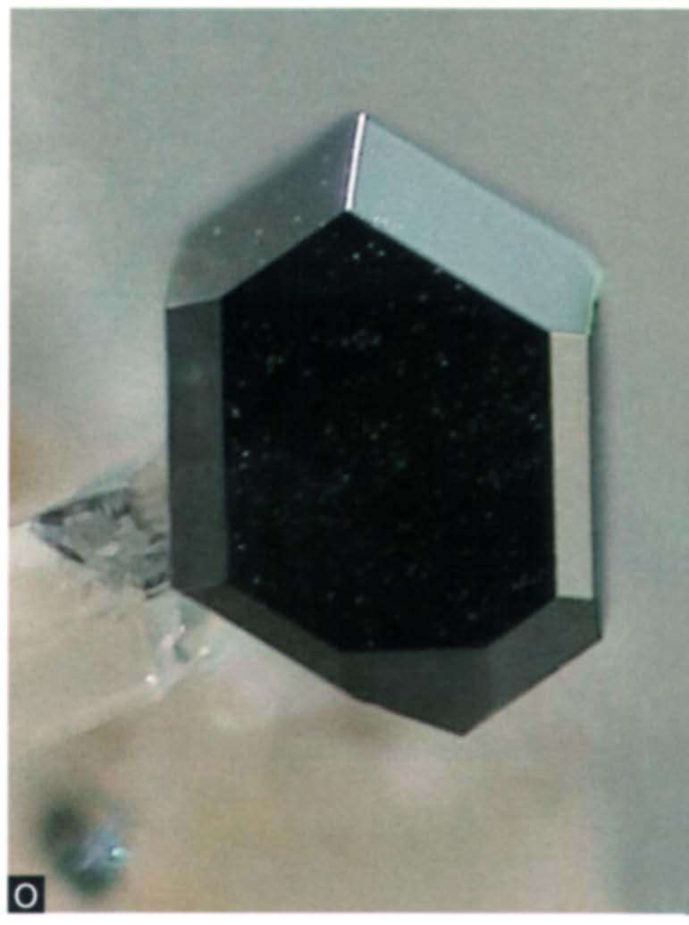 Zwart, isometrisch, vlakkenrijk rutielkristal met een