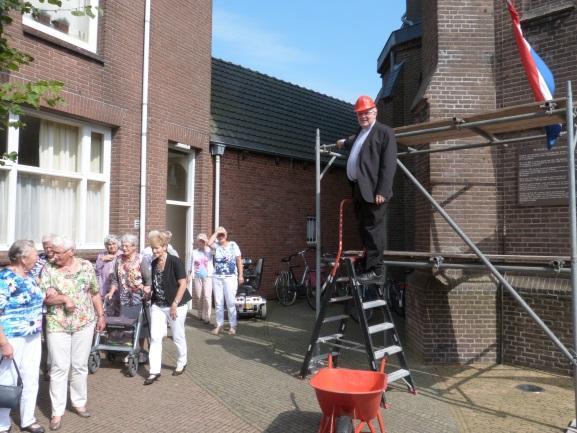 Met een rode bouwhelm op en een hamer beklimt hij de steiger om de eerste voorbereidingen te treffen. Inmiddels staat de toren in de steigers en is begonnen met het uithakken van de voegen.