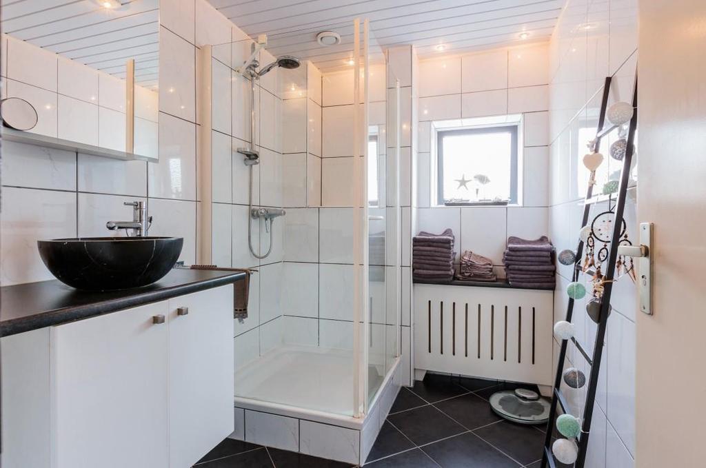 De badkamer: De ruime badkamer is strak en fraai: modern uitgevoerd met een donkere vloertegel en witte wandtegels.
