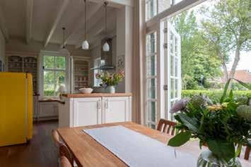 De rustieke keuken heeft een kookunit in landelijke stijl met een massief houten werkblad passend bij de vloer en prachtige handgemaakte tegels van een Amelander kunstenaar boven het elektrisch