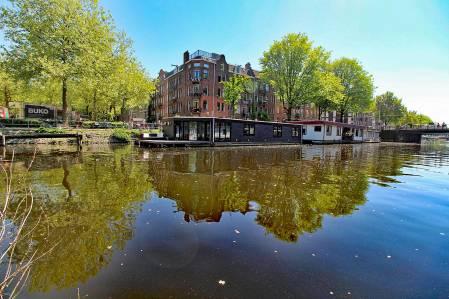 Een fijne living met veel ramen aan de waterzijde en een zonnig inpandig (hoek)balkon.