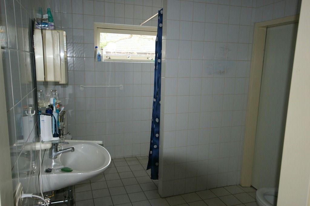 De badkamer is voorzien van een lichte tegel en heeft een ruime inloopdouche,