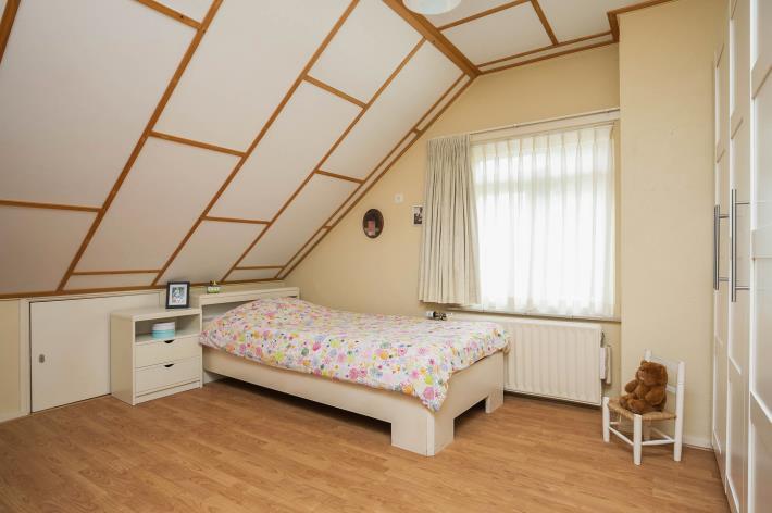 Slaapkamer 2 is afgewerkt met een houten vloer, stucwerk wanden
