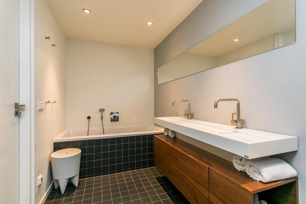 De betegelde badkamer 1 (7m²) is voorzien van een ligbad, douche, dubbele